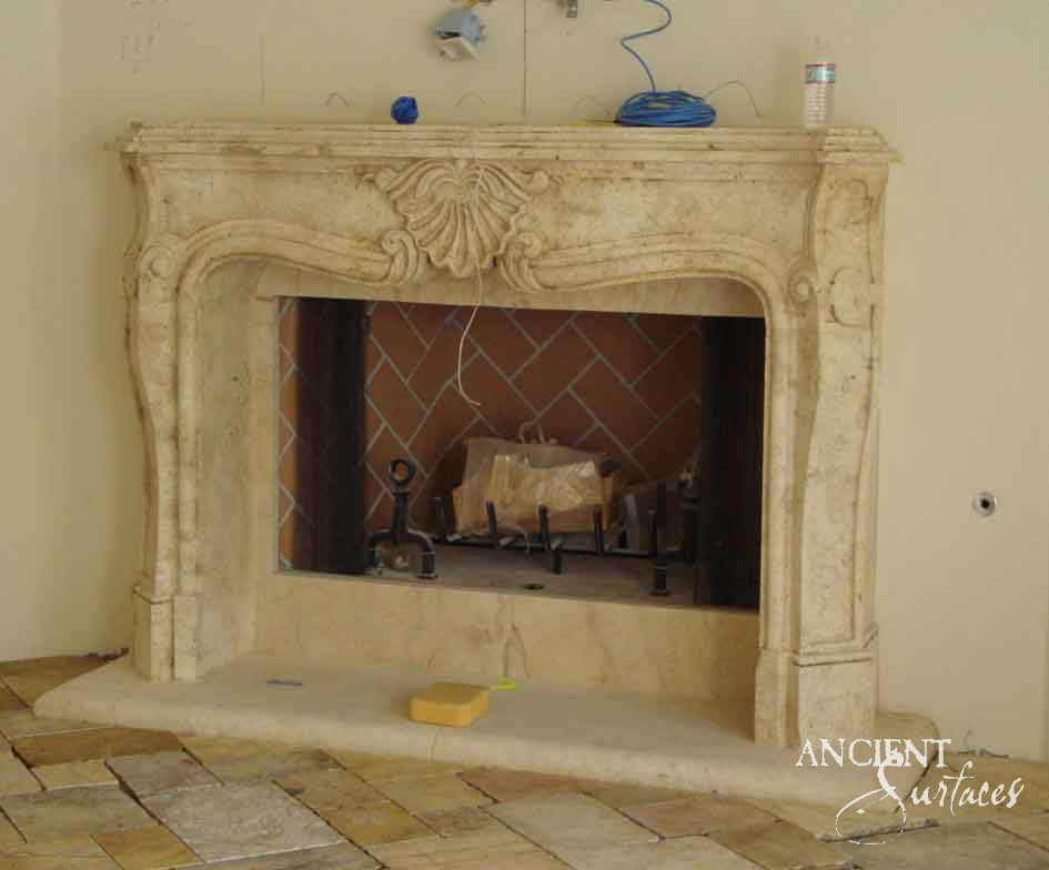 Reclaimed antique limestone mantel from Ancient Surfaces with a carved shell cartouche and scrolled cabriole legs, photographed newly installed