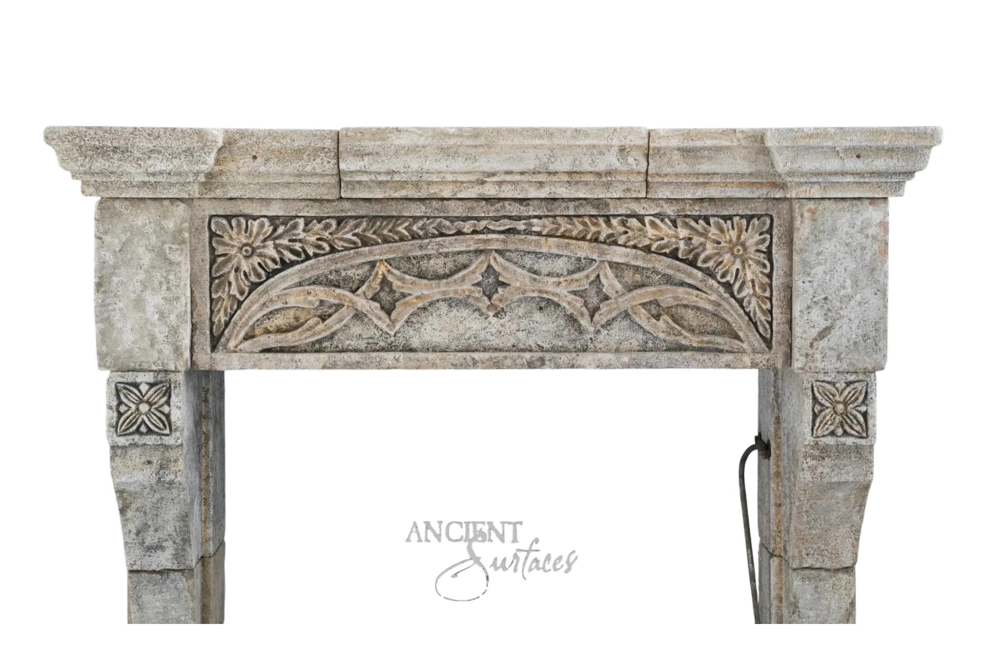 Reclaimed antique limestone mantel from Ancient Surfaces with a carved floral and Gothic arched frieze, photographed against black