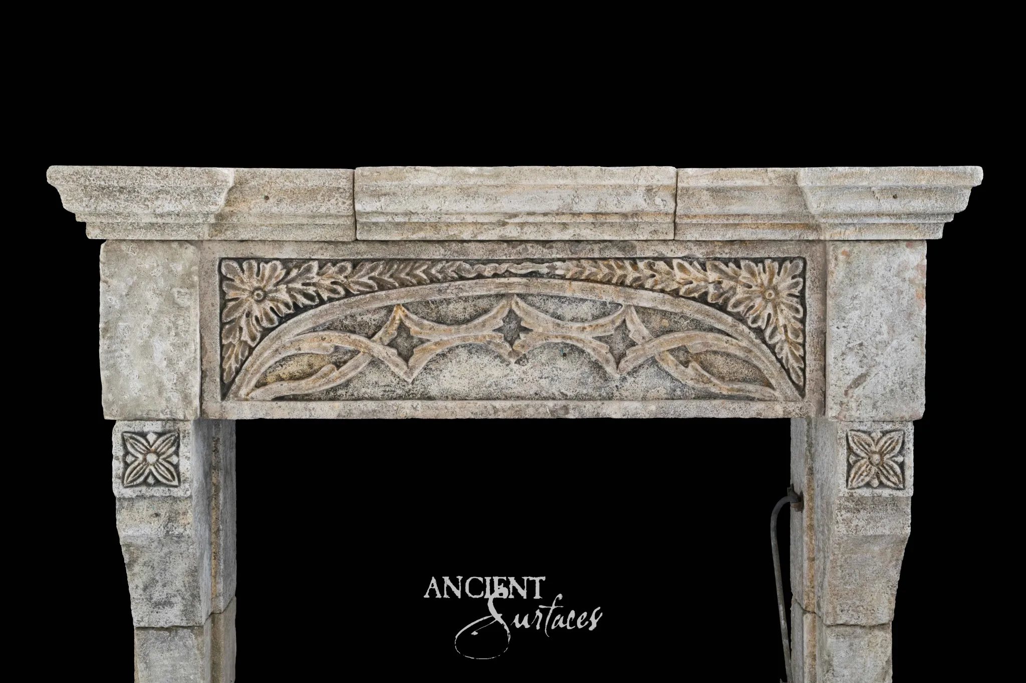 Reclaimed antique limestone mantel from Ancient Surfaces photographed against black with a blind arcade frieze and a central carved rosette