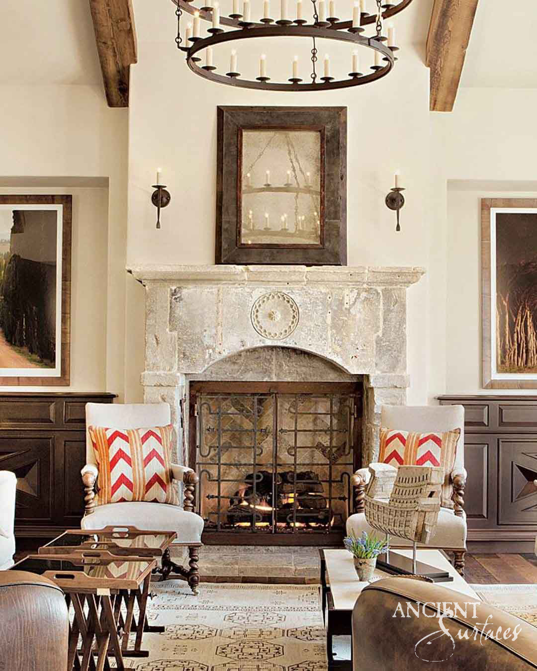 Reclaimed antique limestone mantel from Ancient Surfaces with a carved rosette medallion in a beamed living room between dark wood cabinetry