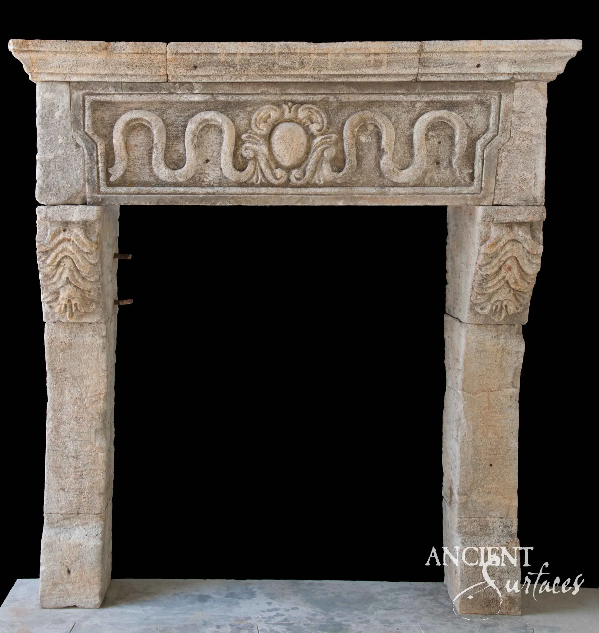 Reclaimed antique limestone mantel from Ancient Surfaces with a ribbon scrolled frieze, a central rosette and fan shaped shell carving at the leg corners