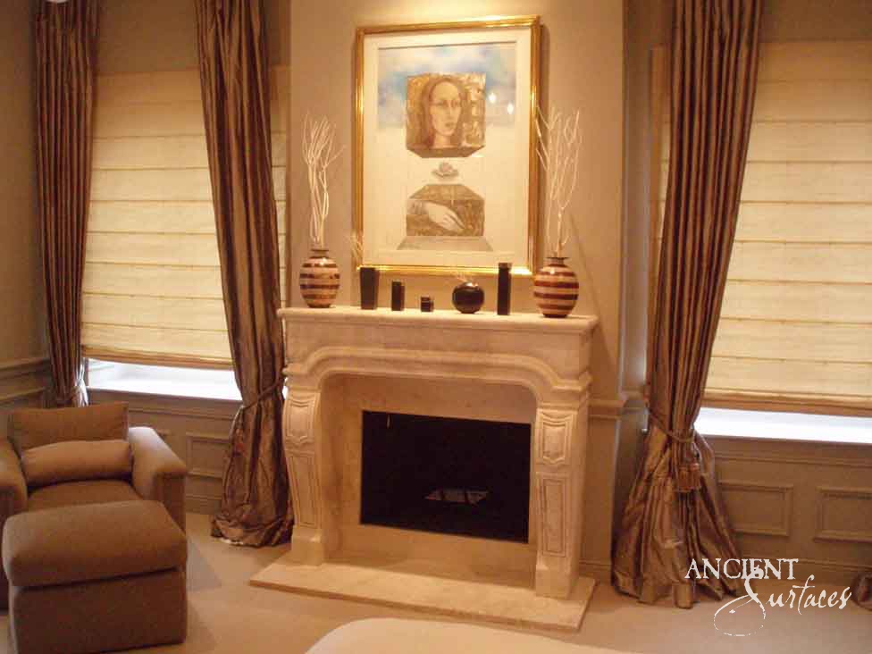 Reclaimed antique limestone mantel from Ancient Surfaces with scrolled cabriole legs in a curtained bedroom suite beneath a large framed portrait